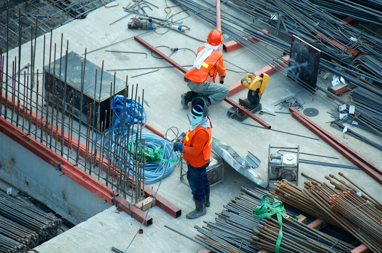 Construction workers in hard hats on a site with steel rebar