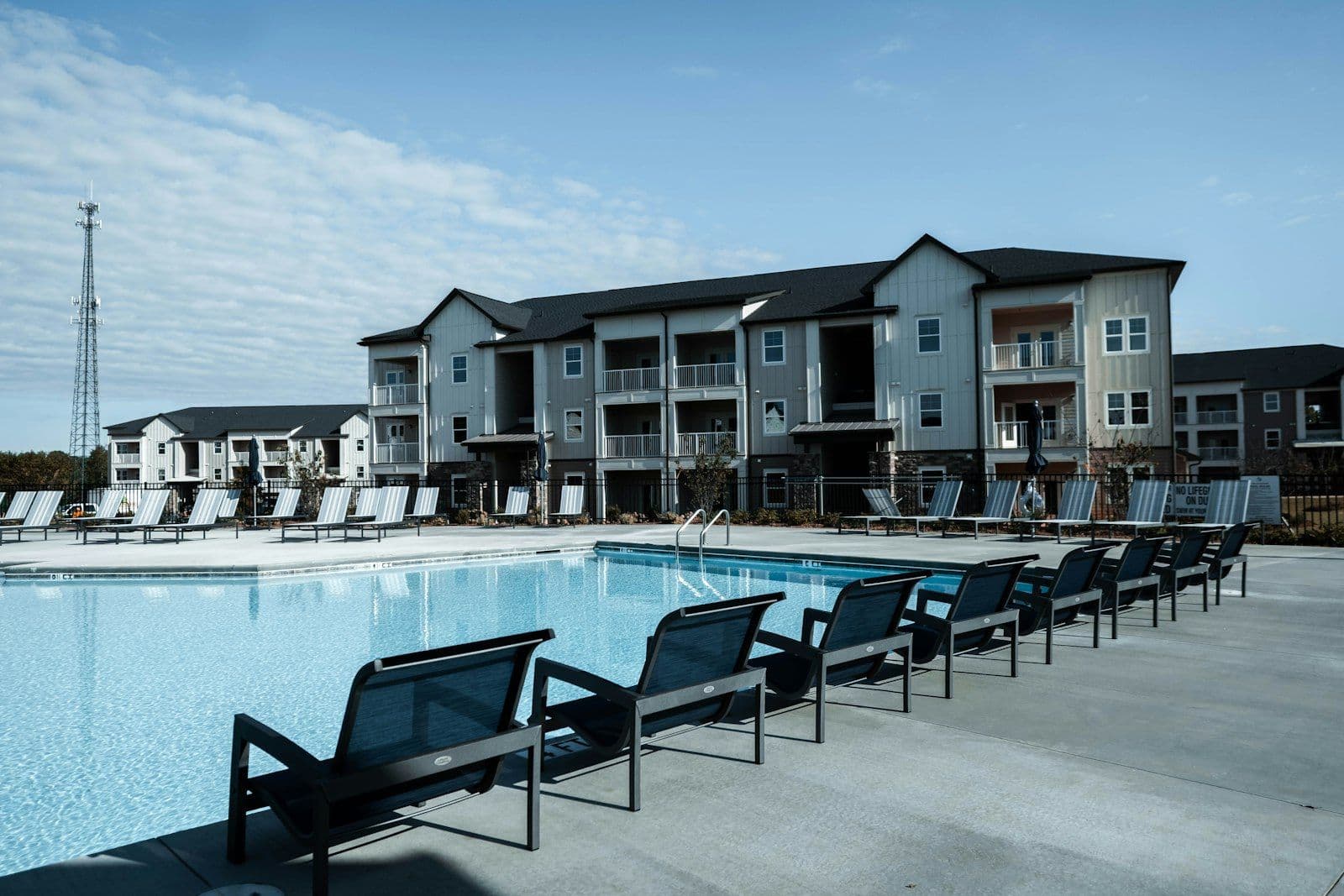 Apartment complex with a pool and lounge chairs on a sunny day