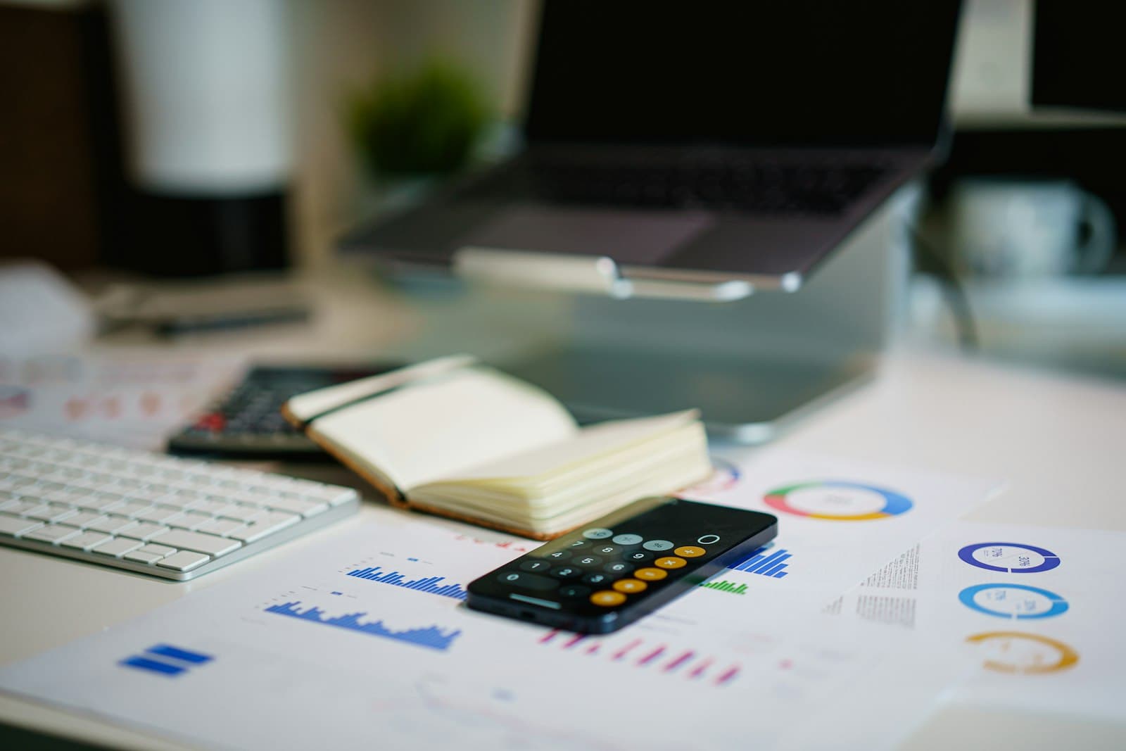 Desk with financial charts, a calculator app, and a notebook