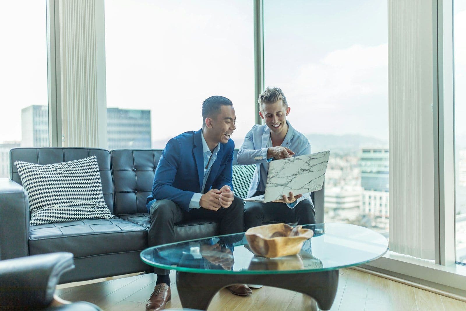 Real estate agent going over listings on a laptop with two clients in a high-rise apartment