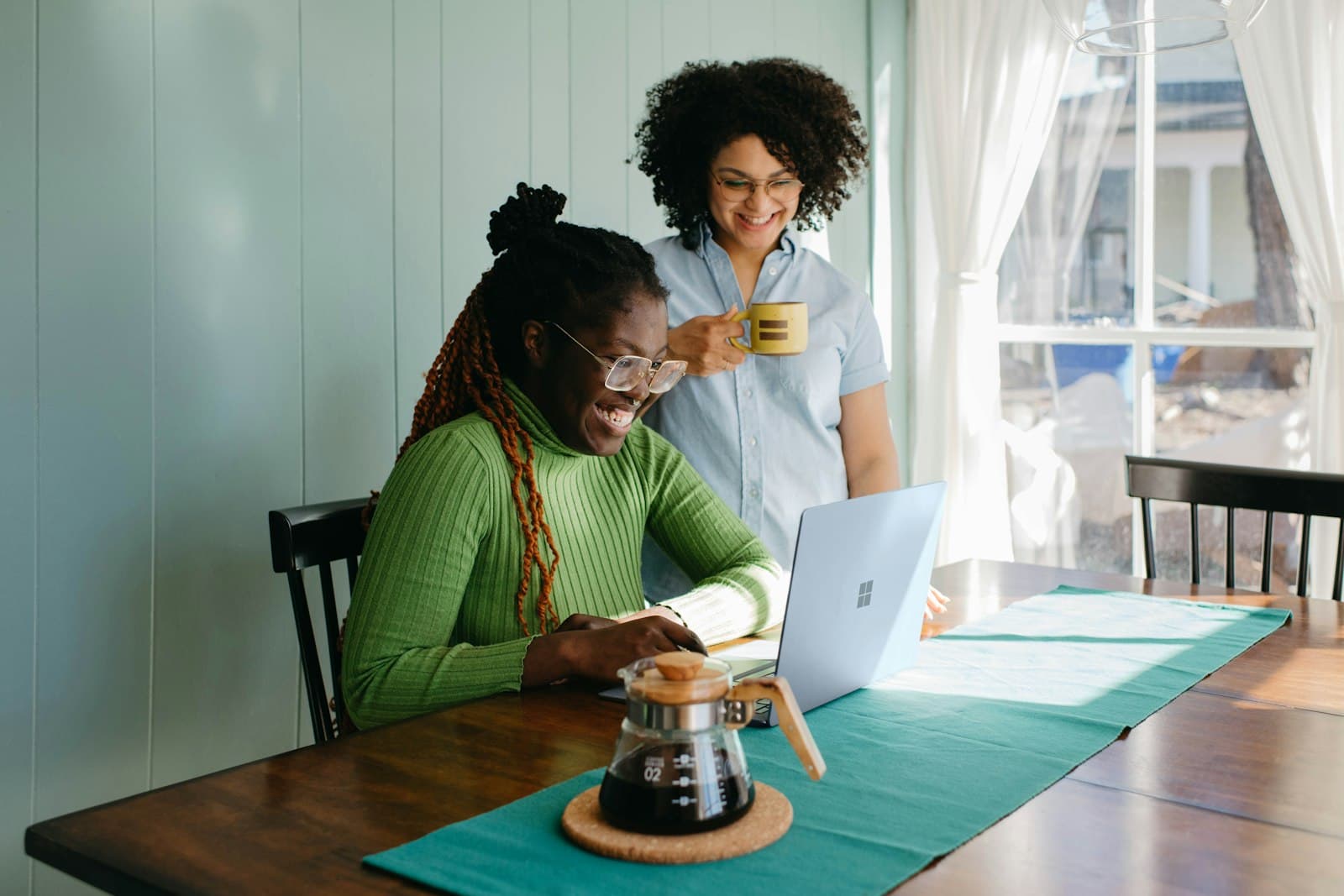 Two colleagues smiling while planning a project on a laptop