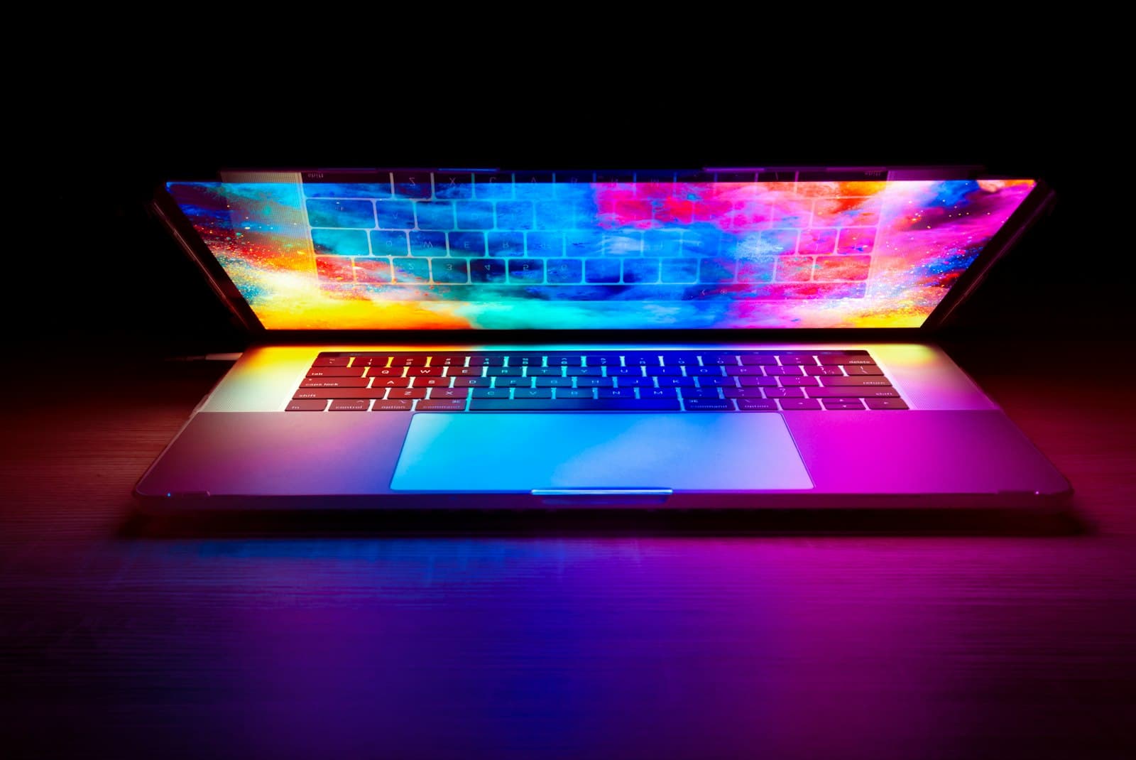 Open laptop lit by a colorful screen in the dark